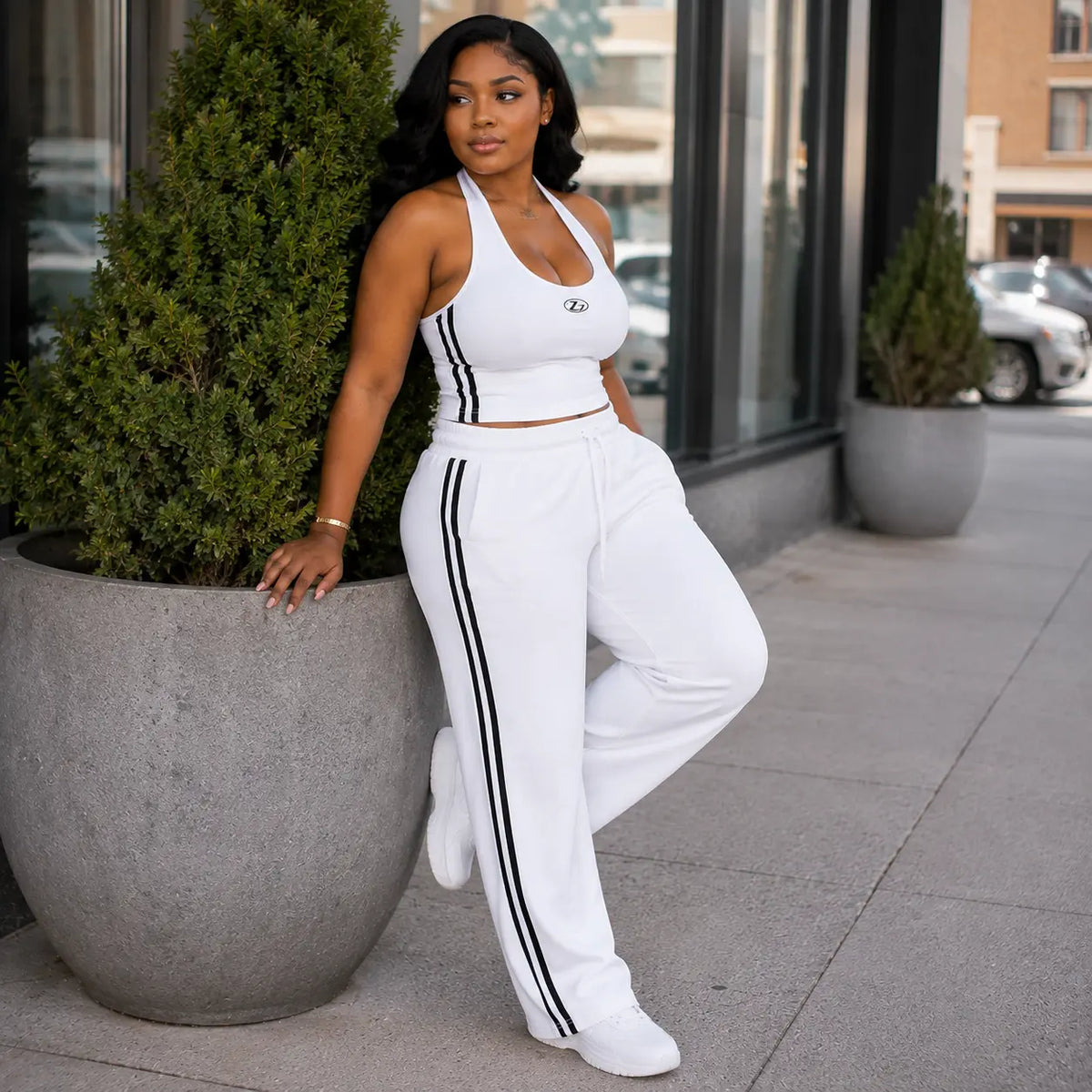 Ensemble sport blanc bandes noires – pose adossée à un pot de fleurs